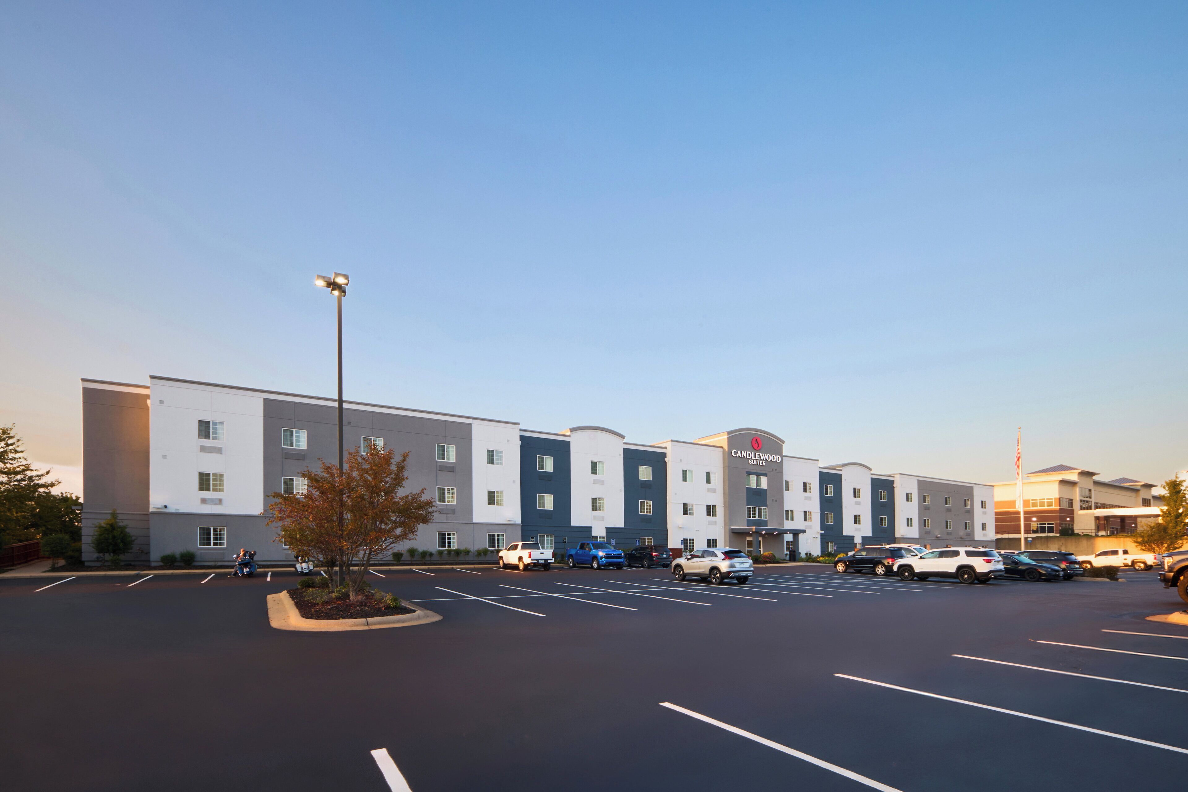 Un hotel con diversi piani, un parcheggio e alcune auto parcheggiate.