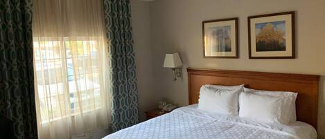 Una habitación de hotel con una cama, una mesita de noche, una lámpara y dos cuadros en la pared.