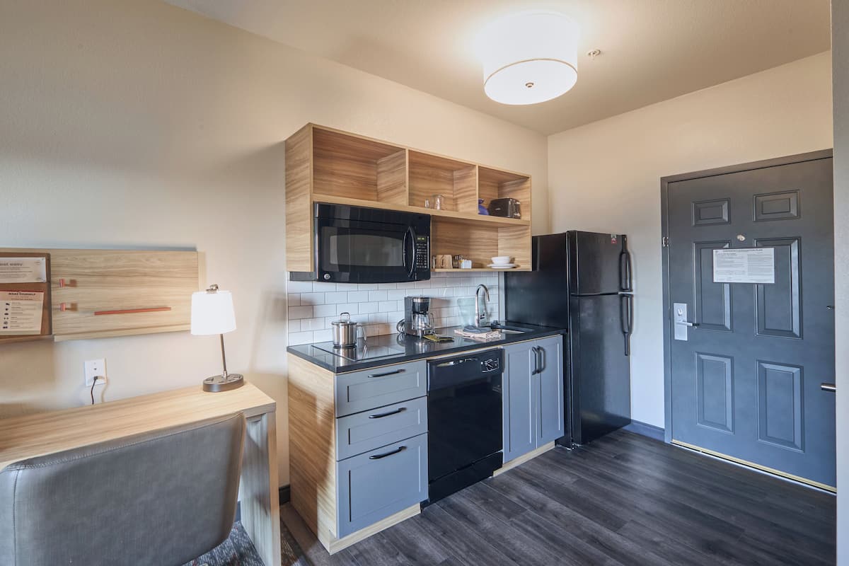 Eine moderne Küche mit Mikrowelle, Backofen und Kühlschrank, Holzschränken und einer Arbeitsplatte mit Lampe.