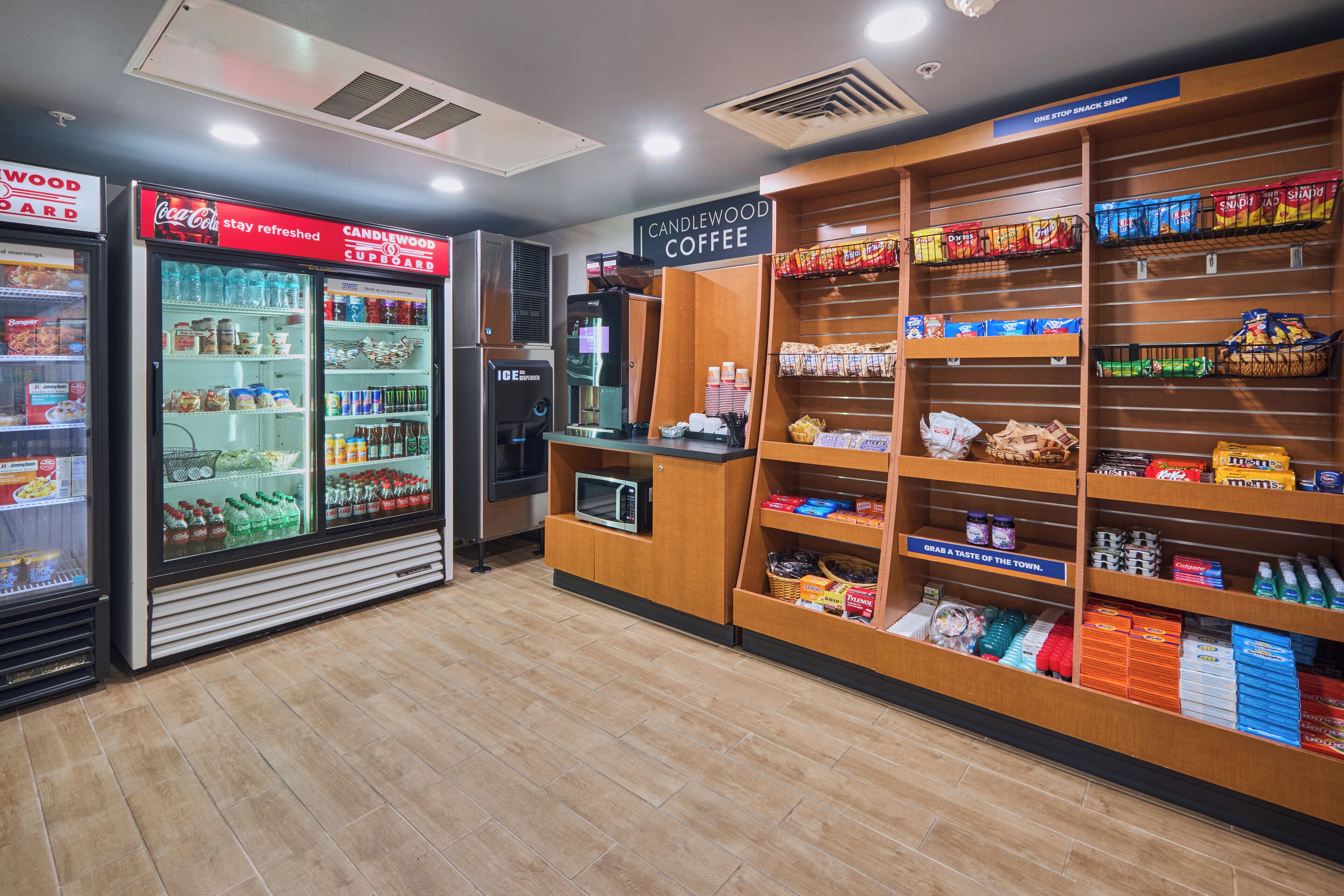 A snack shop with a Coca-Cola refrigerator, a coffee machine, and shelves stocked with snacks and beverages.