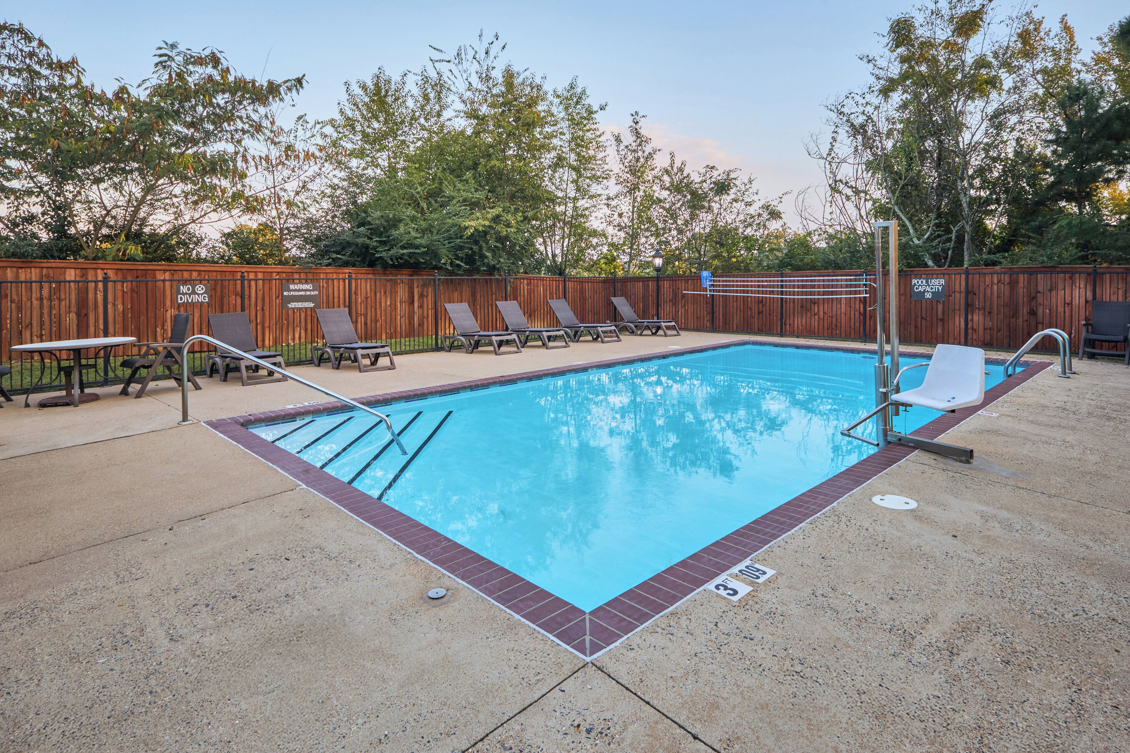 A swimming pool with lounge chairs and a wooden fence.
