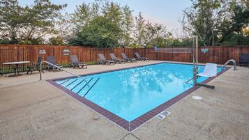 A swimming pool with lounge chairs and a wooden fence.