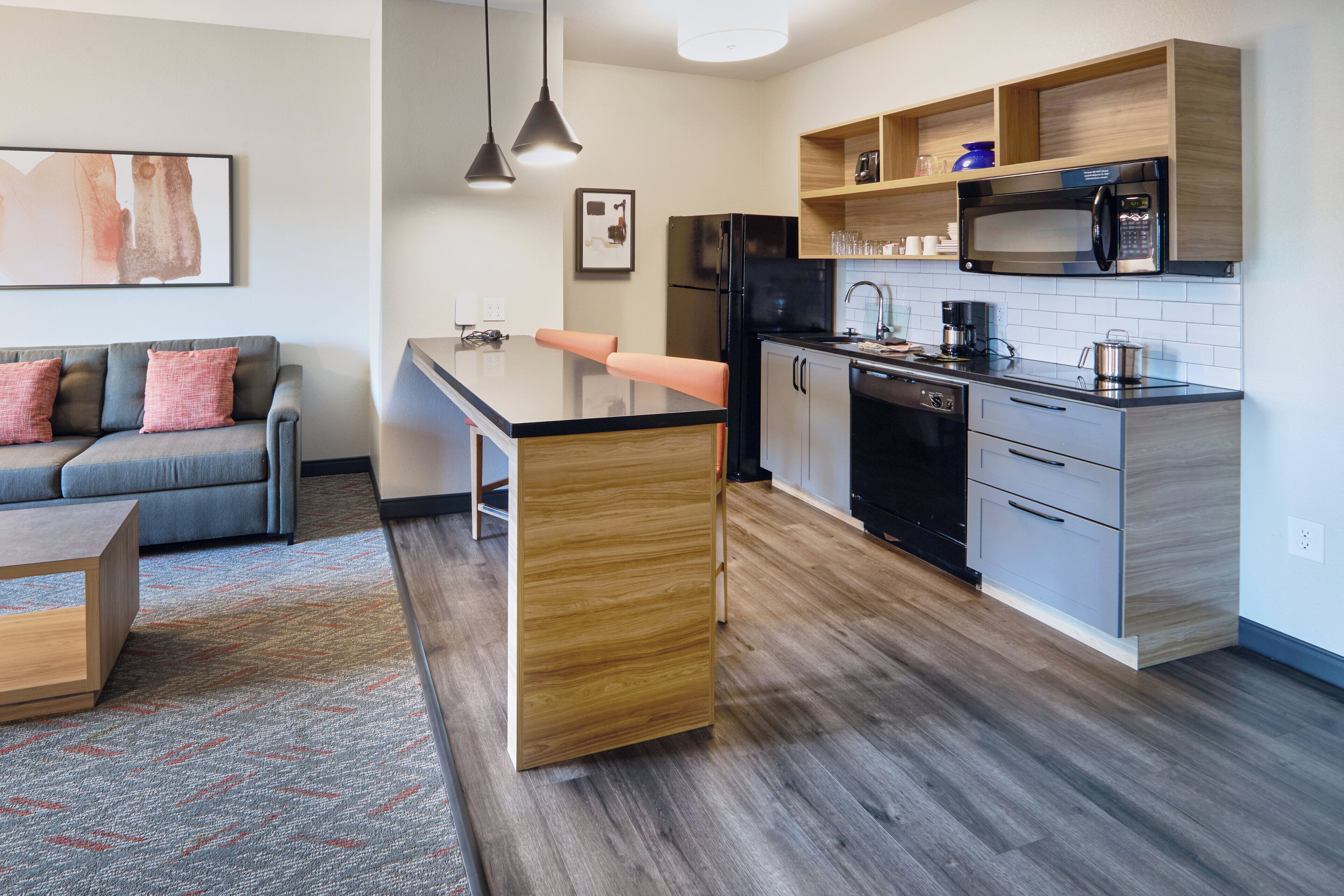A modern kitchen with a central island, wooden cabinets, and a built-in microwave.