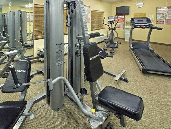 A hotel fitness center with various exercise equipment including a treadmill, elliptical, and weight machines.