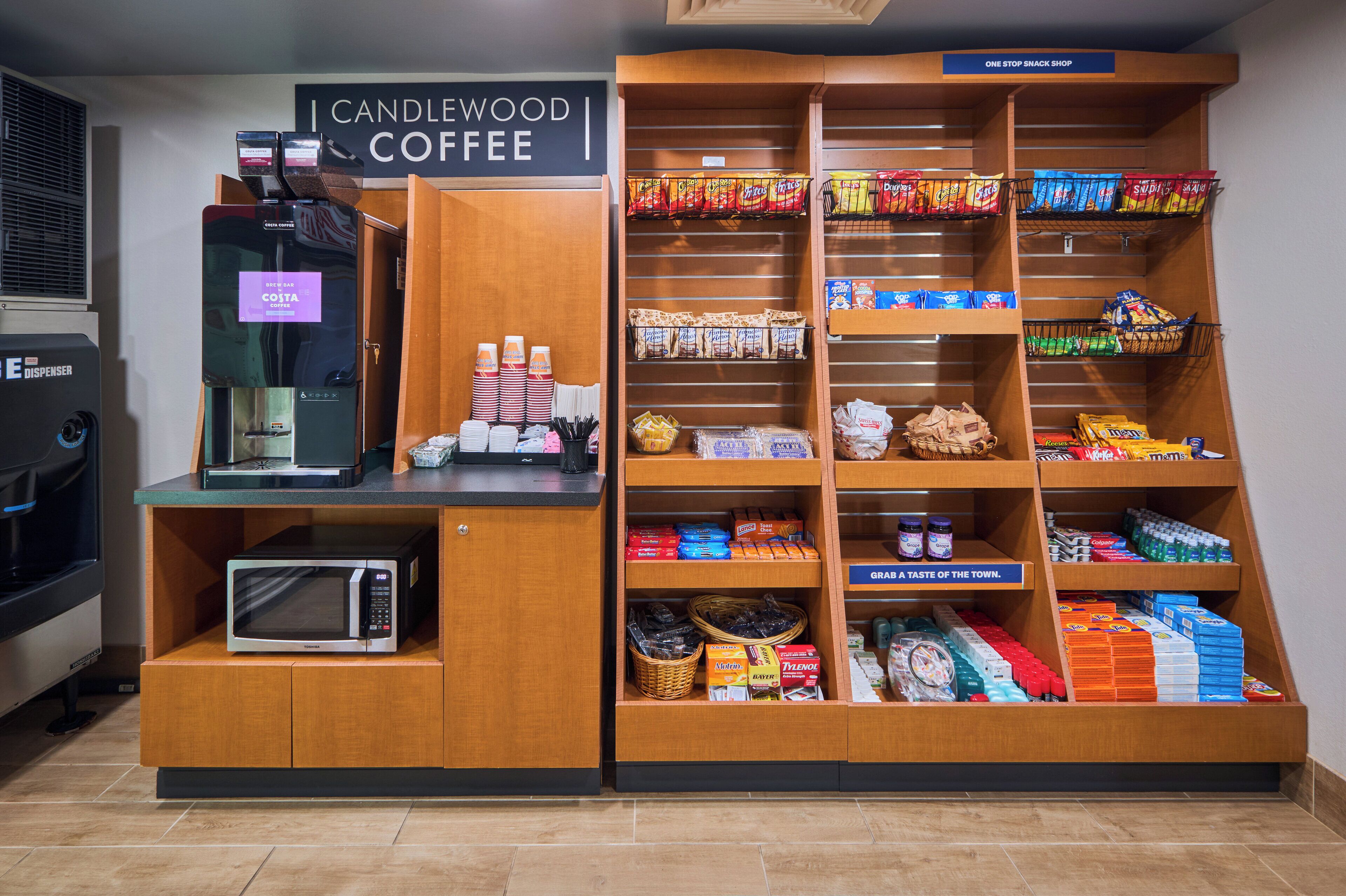 A coffee station with a coffee machine, a microwave, and various snacks and beverages.
