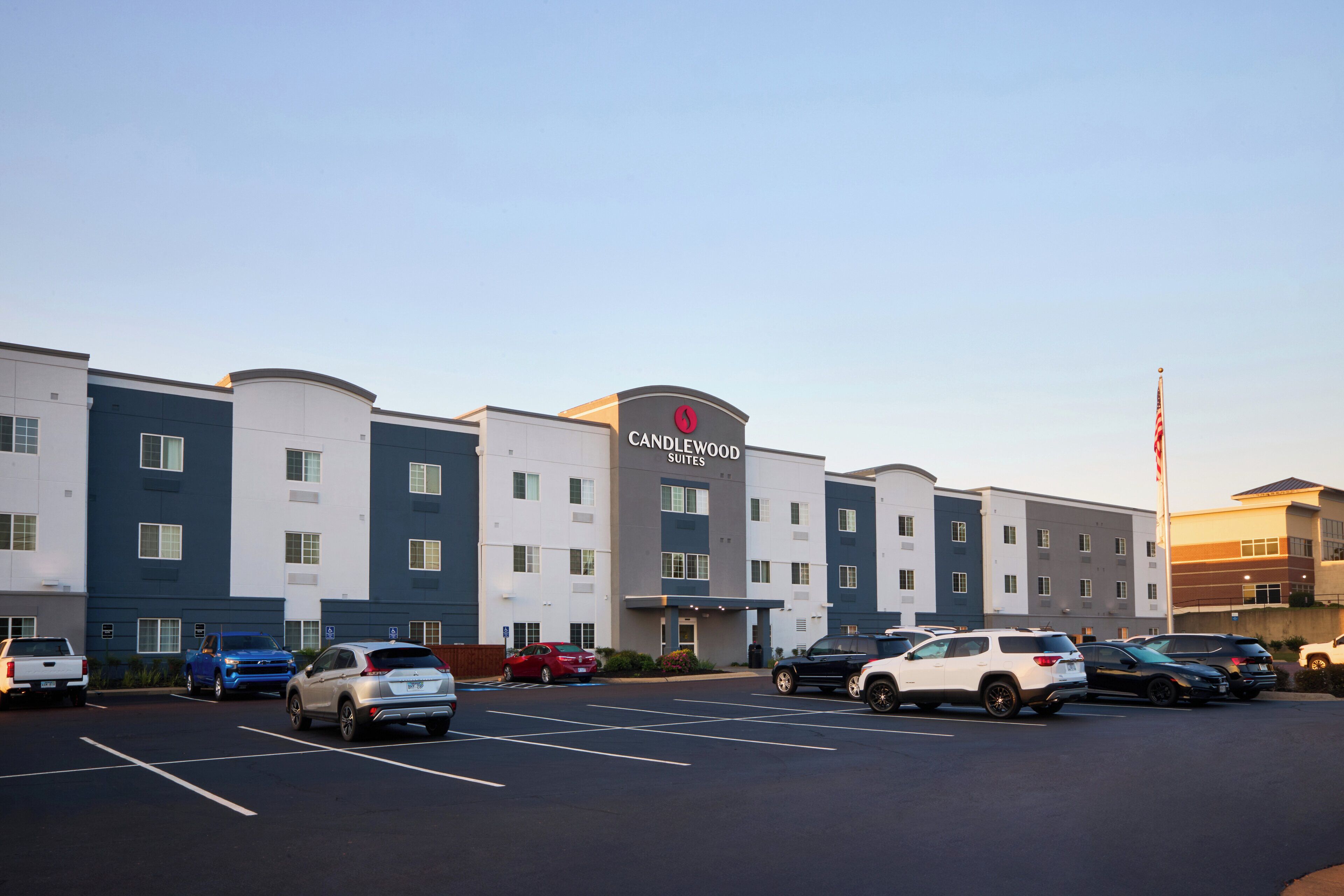 Een hotel met een modern design, met een centrale ingang en meerdere parkeerplaatsen.