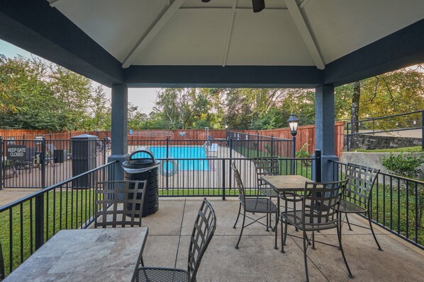 A covered patio with a pool, outdoor furniture, and a fenced area.