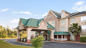 A Country Inn & Suites with a covered entrance, a parking lot, and a landscaped area with a small tree.