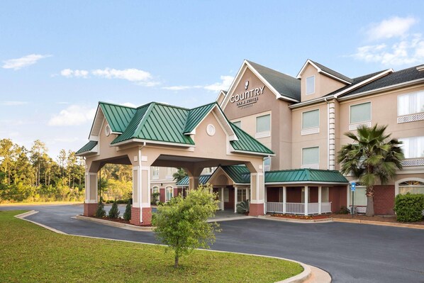 A Country Inn & Suites with a covered entrance, a parking lot, and a landscaped area with a small tree.