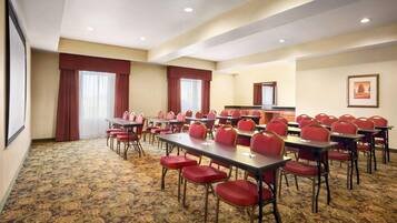 Une salle de conférence dotée de plusieurs tables et chaises, d’un sol recouvert de moquette et d’un grand miroir au mur.