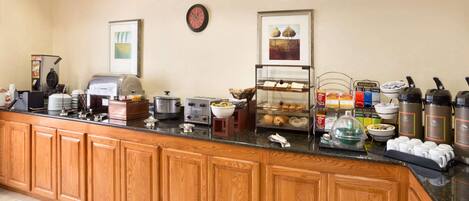 A breakfast bar with a coffee maker, toaster, and various food items.