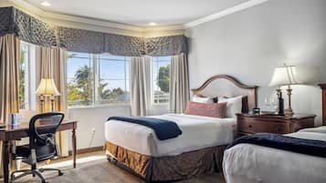 Une chambre d’hôtel avec un grand lit, un bureau avec une chaise, une table de chevet avec une lampe et une vue sur l’extérieur par la fenêtre.