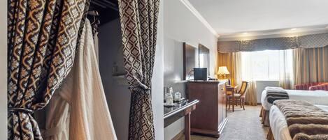 A hotel room with a bed, a desk, a chair, and a wardrobe.