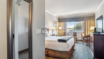 A hotel room with a large bed, two bedside tables with lamps, a desk with a chair, a television, and a window with curtains.
