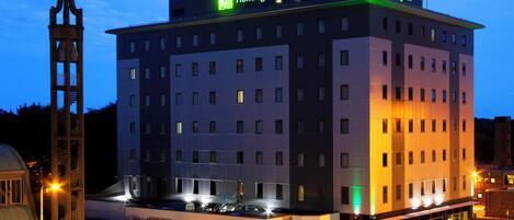 A Holiday Inn hotel with a modern design, featuring a prominent tower and a well-lit facade.