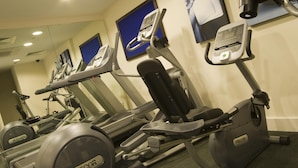 A gym with stationary bikes and elliptical machines, equipped with digital displays.