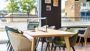 A modern cafe interior with a wooden table, various chairs, and a laptop on the table.