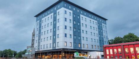 A multi-story hotel with a modern design, featuring a prominent entrance and a visible sign for the Holiday Inn.