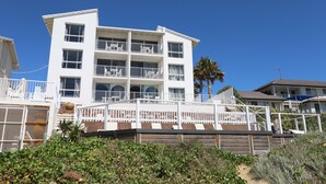 A multi-story hotel with balconies, a sandy beach in the foreground, and a clear blue sky. - Don Pancho by the Beach (Bargara)