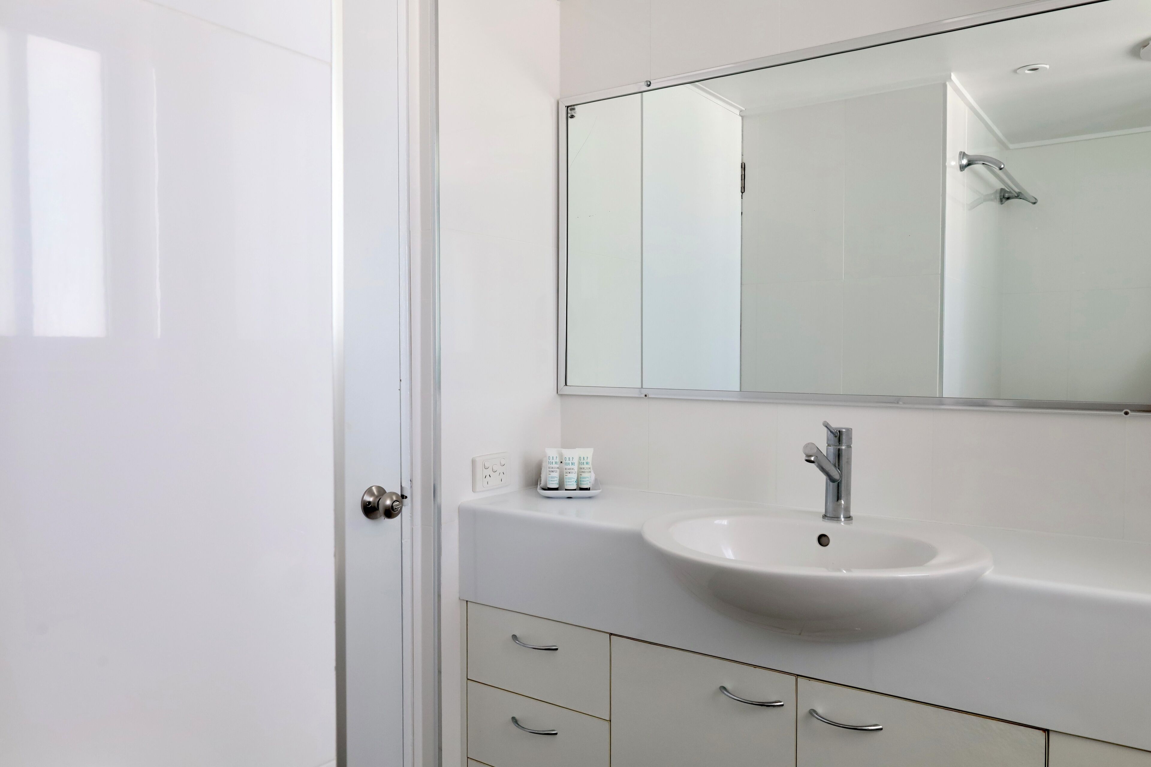 A bathroom with a white sink, a mirror, and a shower.