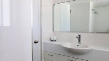 A bathroom with a white sink, a mirror, and a shower.