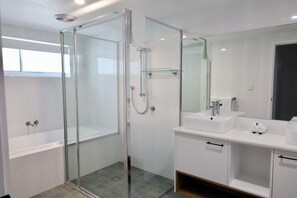 Un baño moderno con ducha de vidrio, bañera y tocador con espejo.