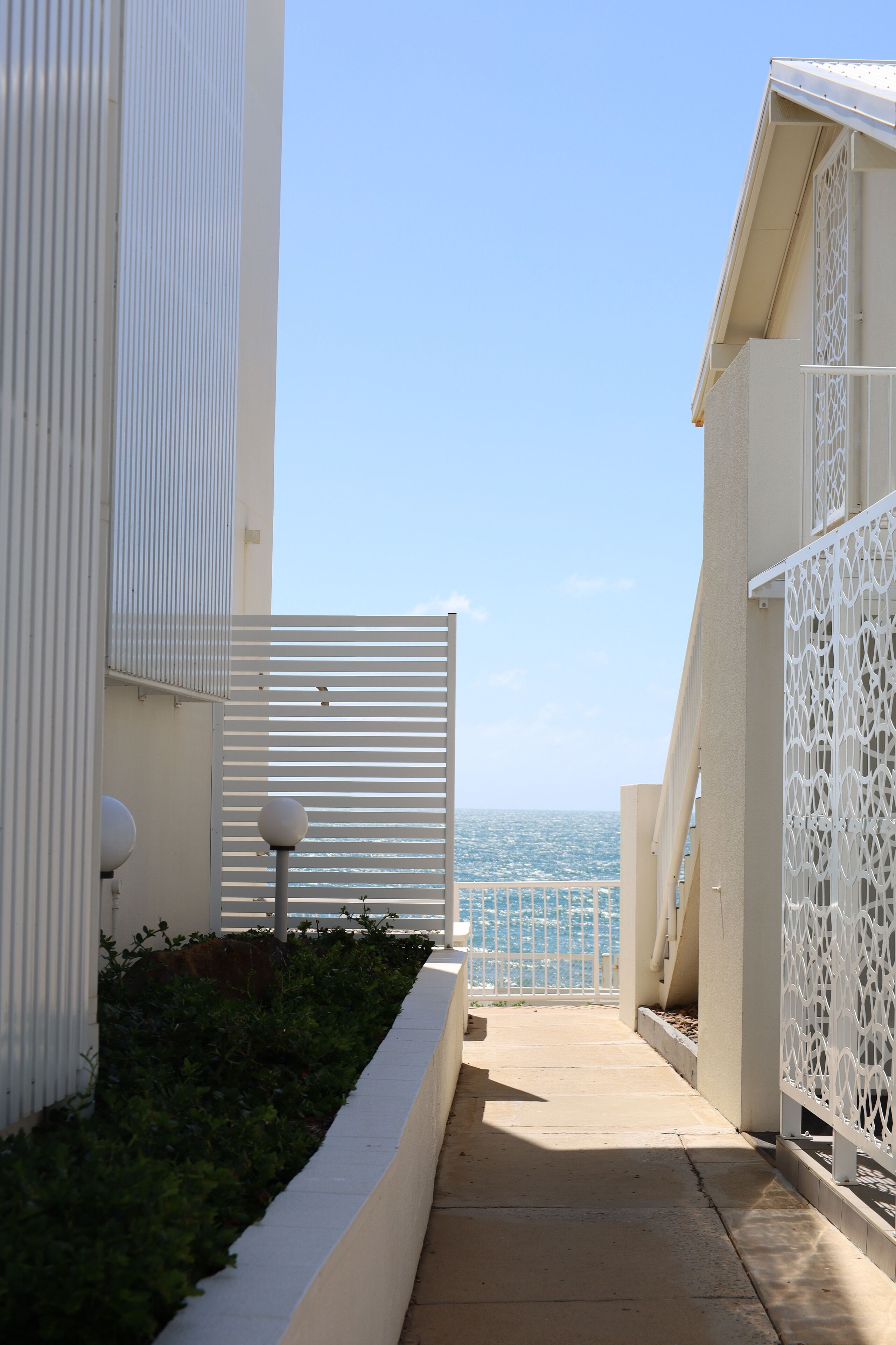 Ein schmaler Pfad führt zu einem Balkon mit Blick aufs Meer.