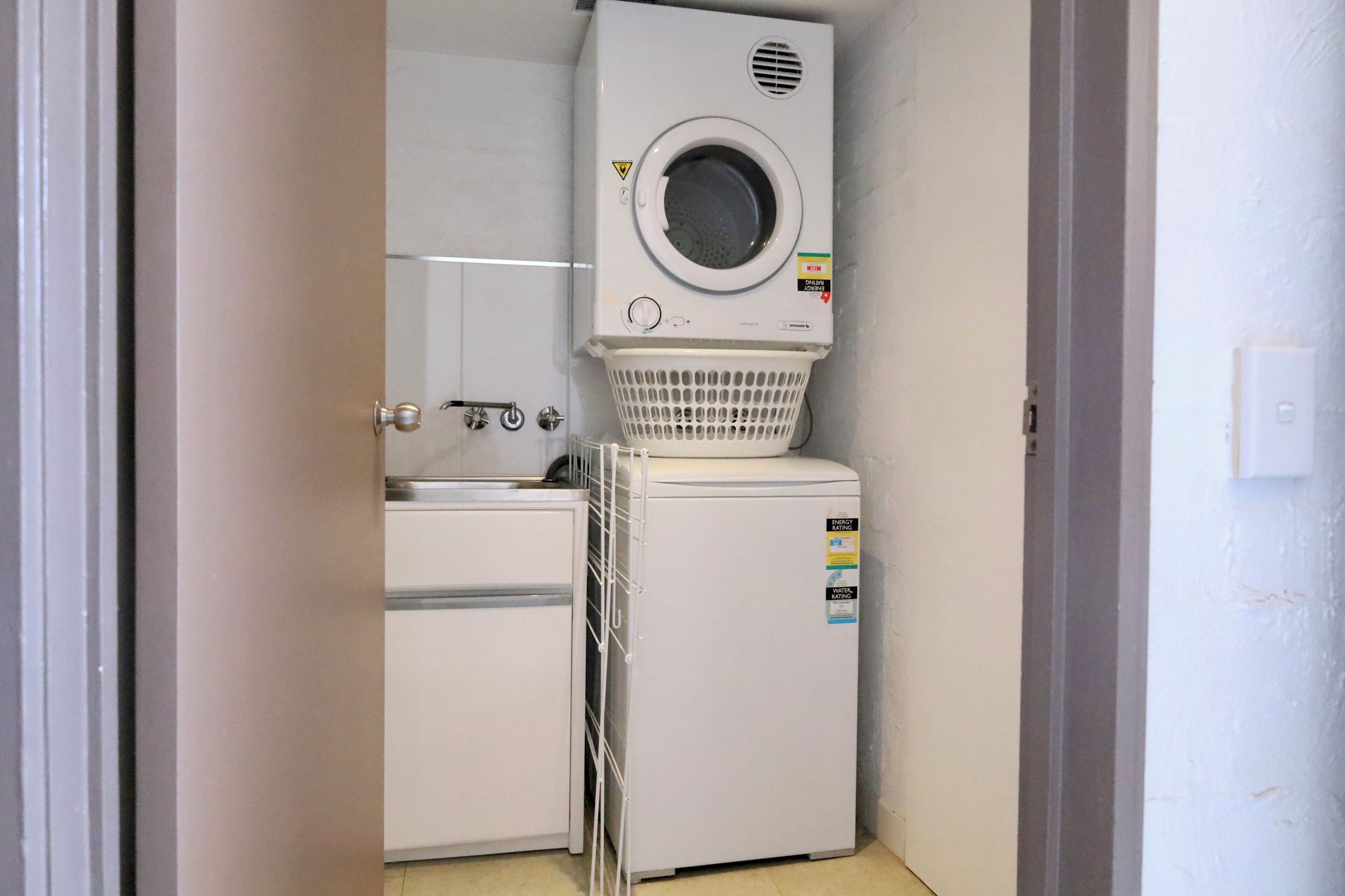Une petite buanderie équipée d’un lave-linge, d’un sèche-linge et d’un étendoir.