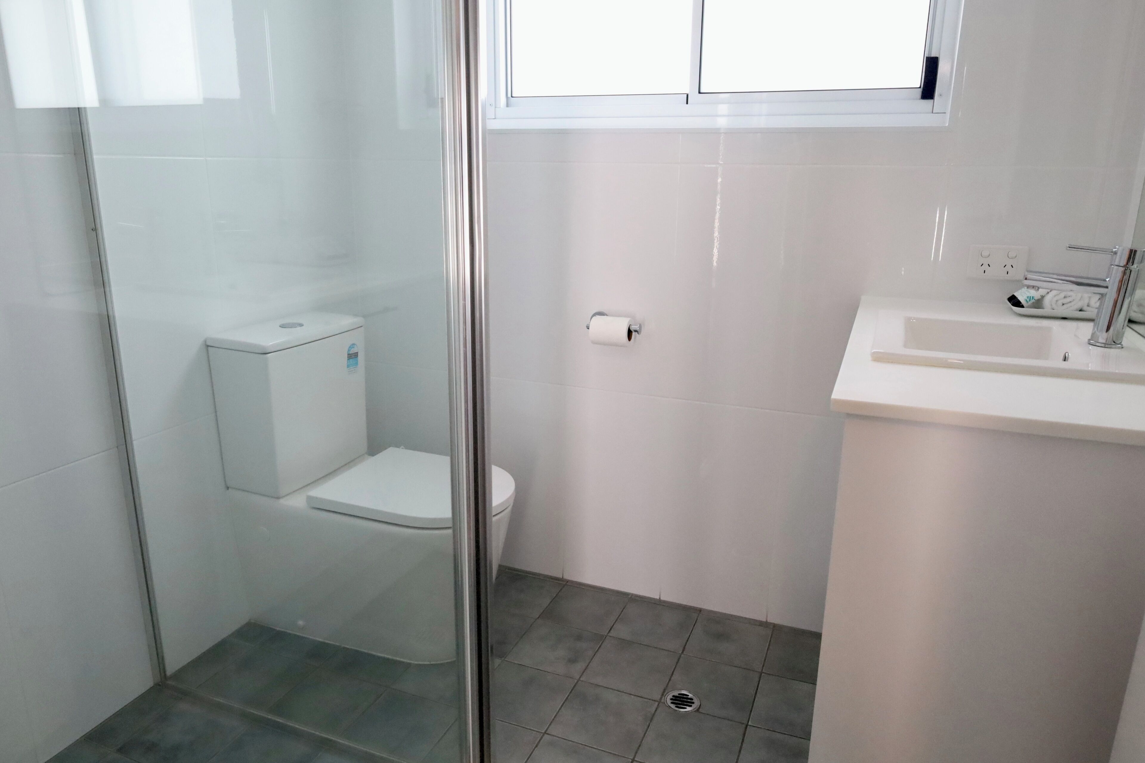 A modern bathroom with a glass shower enclosure, a white toilet, and a sink with a mirror.