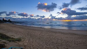 A beach with a wooden bench, ocean waves, and a sunset. - Don Pancho by the Beach (Bargara)