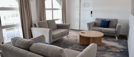 Ein modernes Wohnzimmer mit zwei Sofas, einem Couchtisch und Blick durch große Fenster.