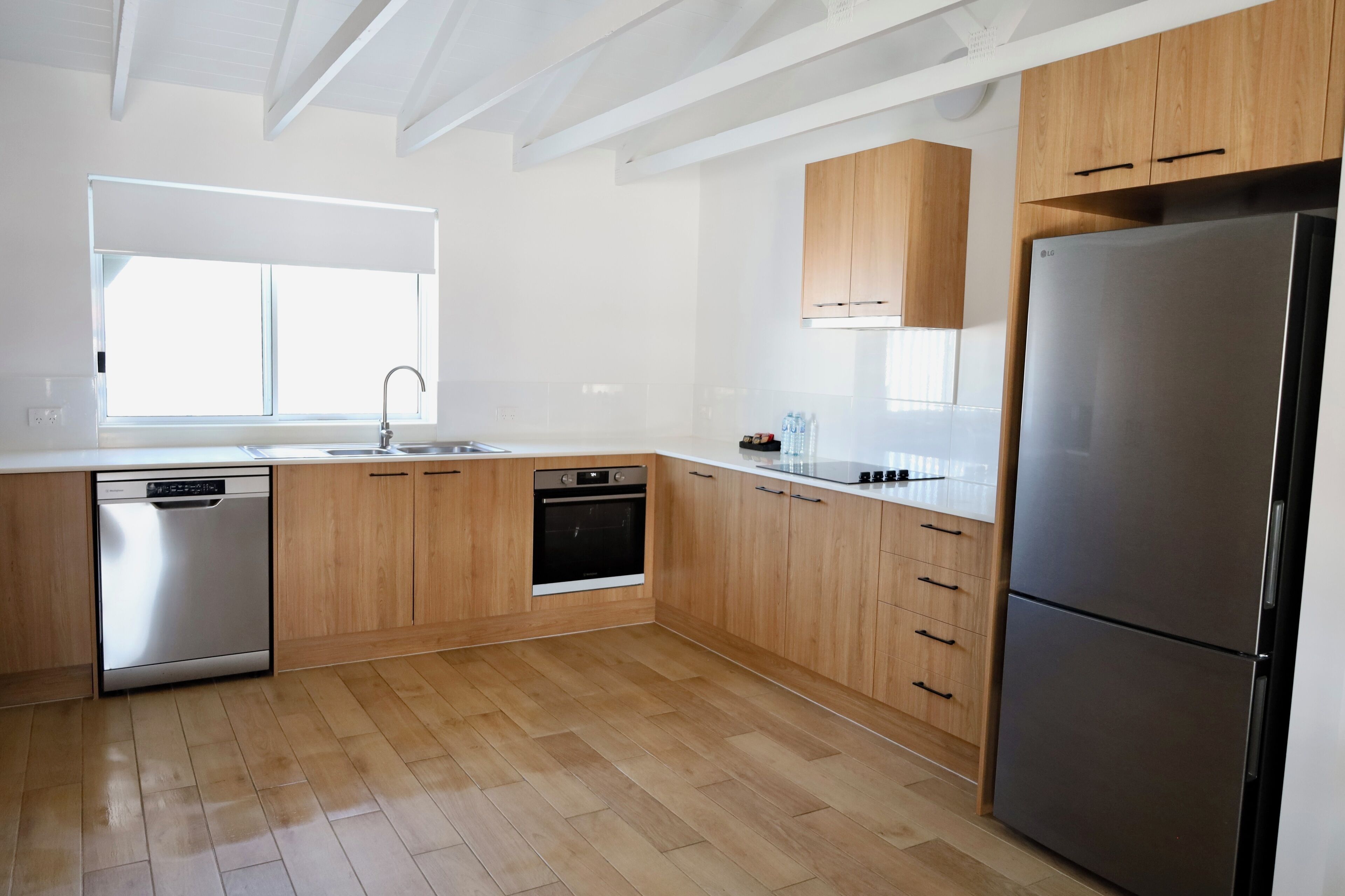 A modern kitchen with wooden cabinets, stainless steel appliances, and a large window.