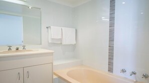 A modern bathroom with a bathtub, a sink, and a mirror. - Beach House Seaside Resort Coolangatta (Coolangatta)
