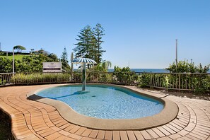 A swimming pool with a curved edge, surrounded by a brick deck, and a sign indicating 'Beach House'. - Beach House Seaside Resort Coolangatta (Coolangatta)