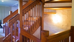 A wooden staircase with a handrail and a light source on the wall. - Palm Court Noosa (Noosa Heads)