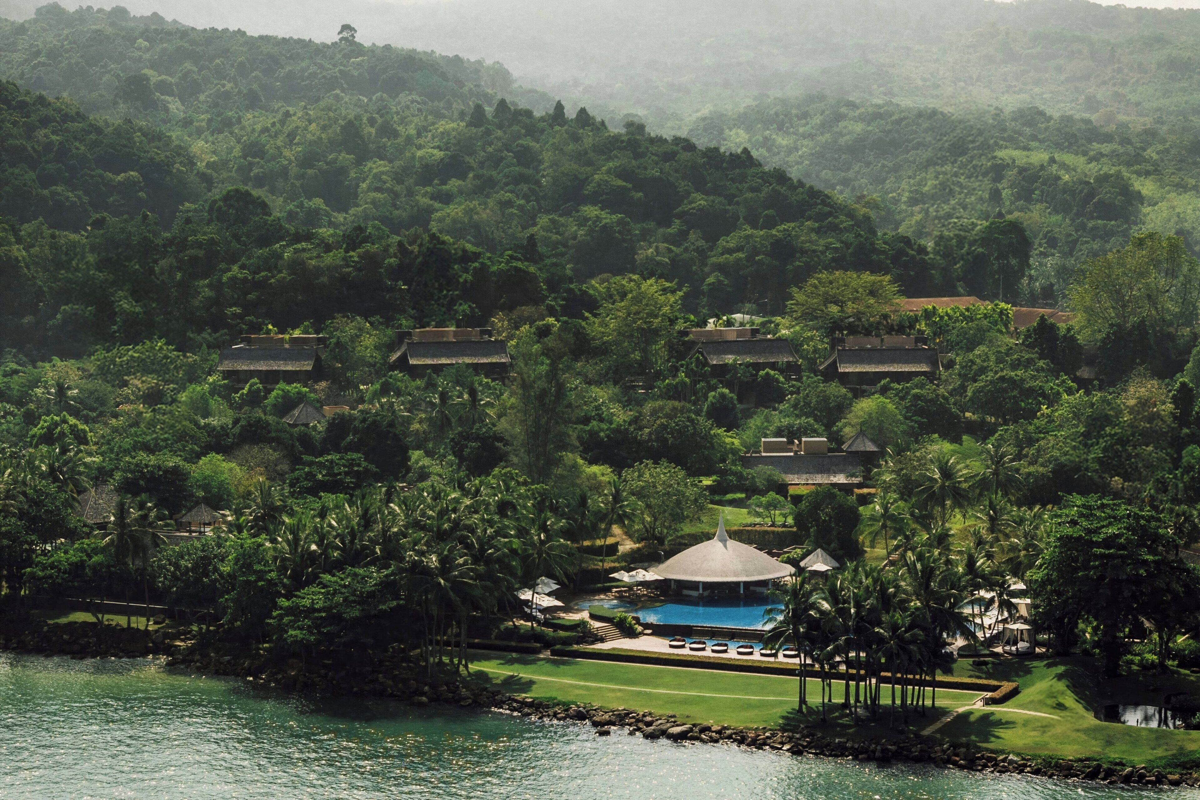 A resort with a swimming pool, lush greenery, and traditional-style villas.