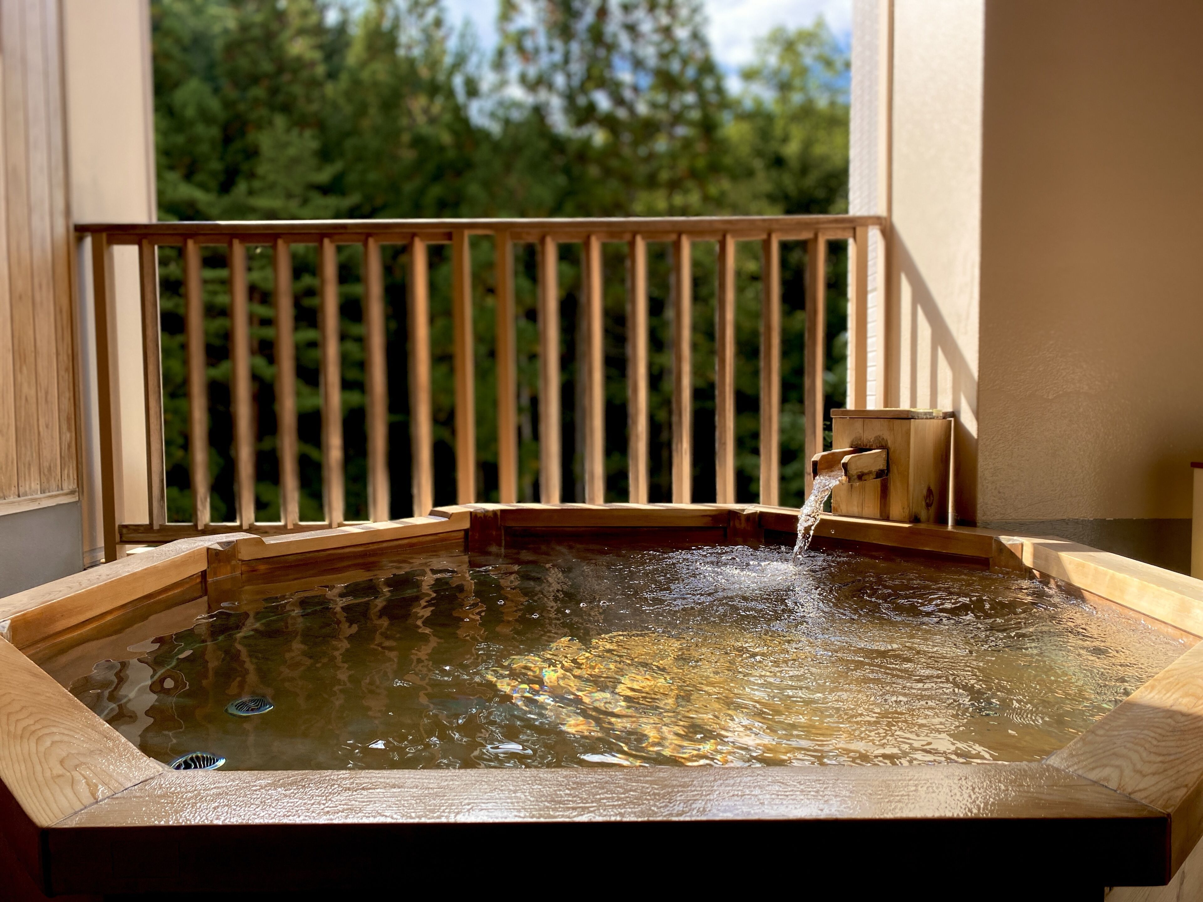 Jacuzzi amb barana de fusta i estructura de fusta amb un grifo.