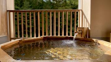 Jacuzzi amb barana de fusta i estructura de fusta amb un grifo.