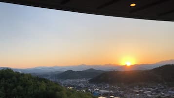 A sunset view from a covered area overlooking a town with mountains in the background.