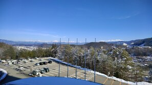A parking lot with snow-covered trees and mountains in the background.