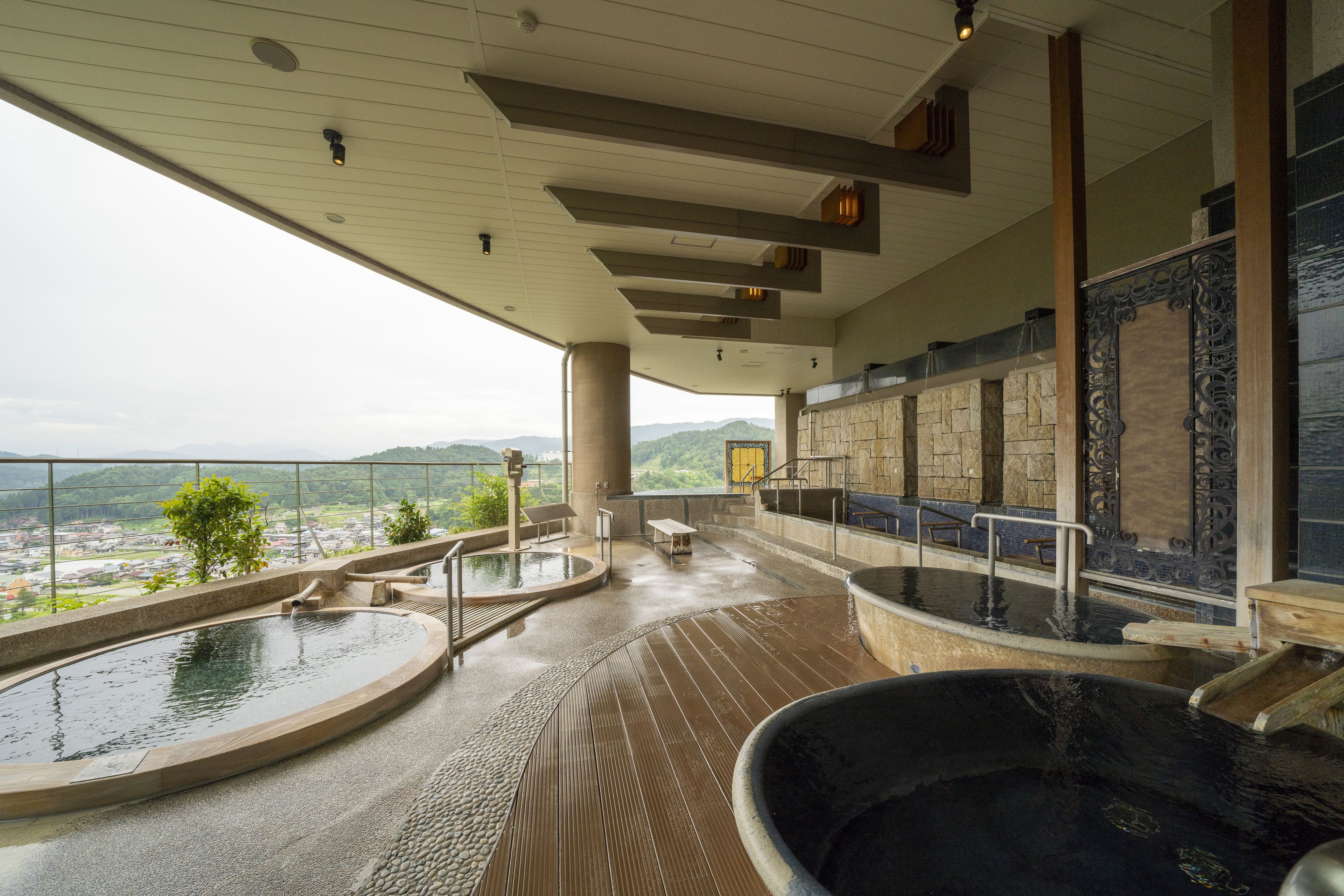 A spa area with a large hot tub, a smaller hot tub, and a pool, with a view of the landscape.