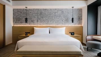Una habitación de hotel con una cama grande, dos mesitas de noche con lámparas, un cabecero de madera y una pared con estampado.