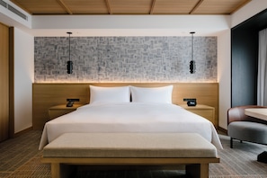 A hotel room with a large bed, two bedside tables with lamps, a wooden headboard, and a patterned wall. - Hilton Takayama Resort (Takayama)
