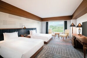 Une chambre d’hôtel avec deux lits, un bureau, une chaise et une vue sur l’extérieur.