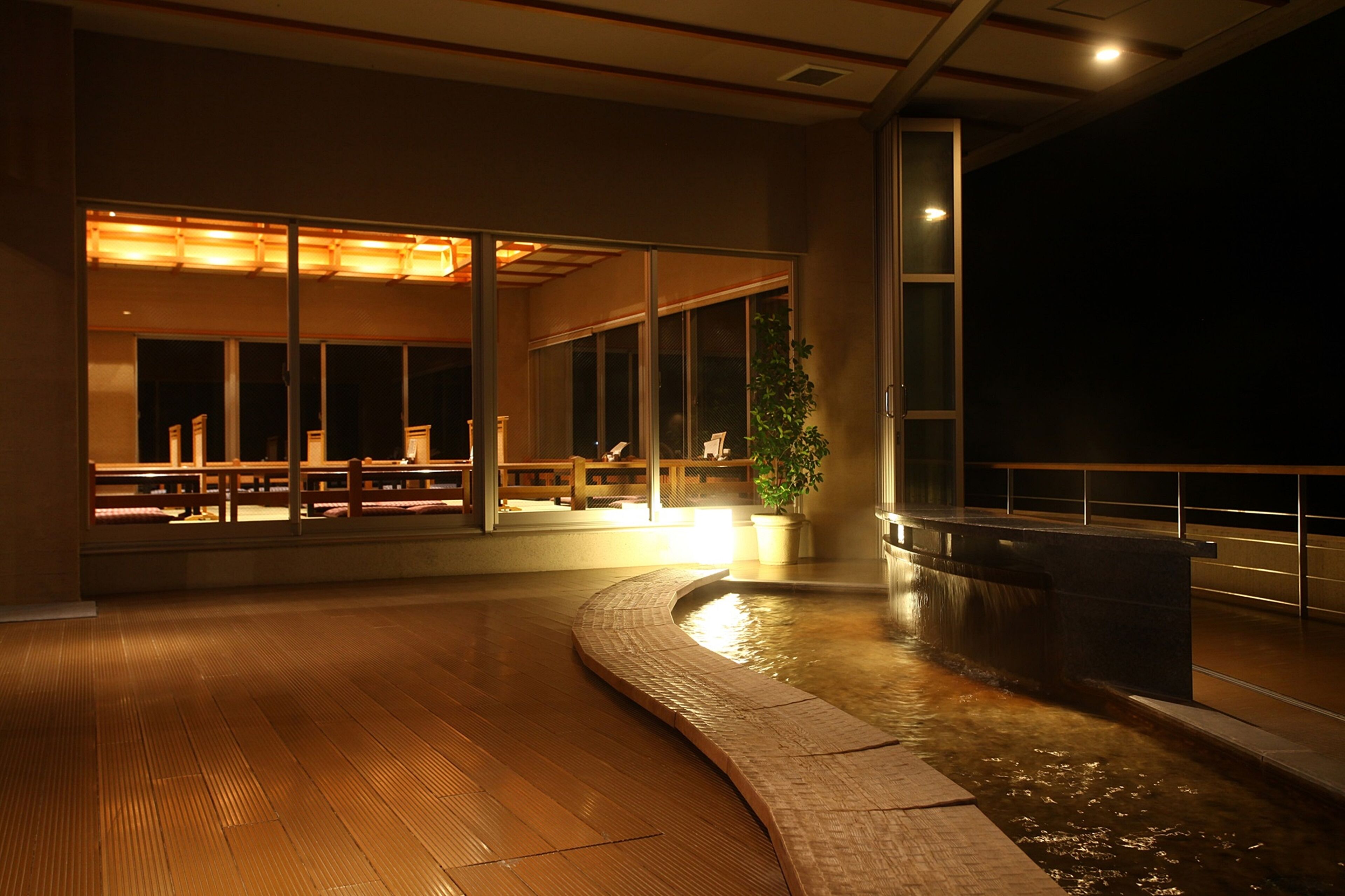An indoor space with a wooden floor, a water feature, and a seating area with benches.
