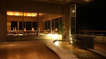 An indoor space with a wooden floor, a water feature, and a seating area with benches.