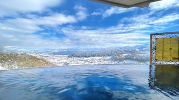 An infinity pool with a clear view of a snowy landscape and mountains in the distance.