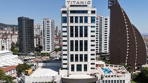 A modern hotel with a prominent "Titanic" sign, surrounded by high-rise buildings and a pool area. - Titanic Business Kartal (Istanbul)