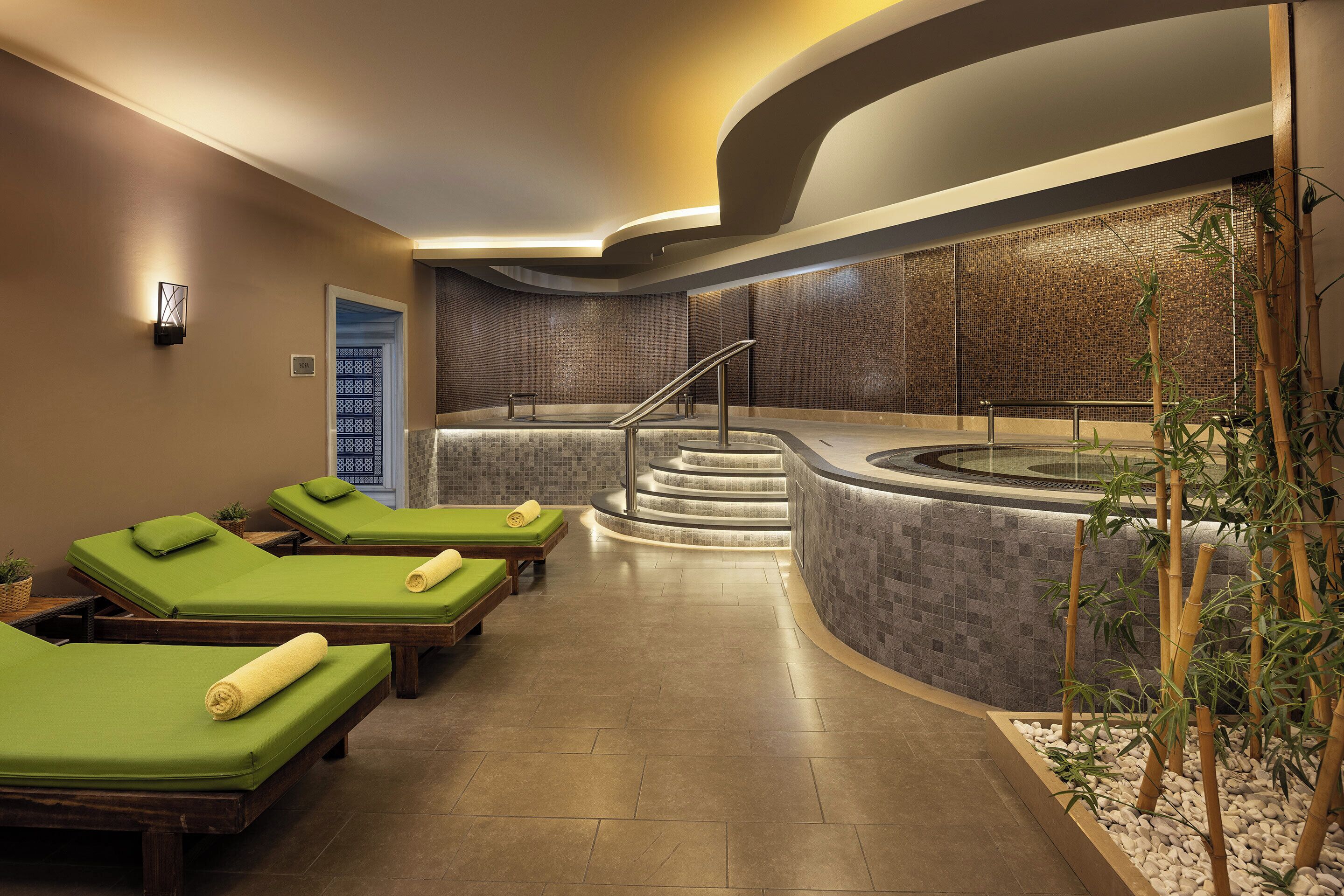 A spa area with massage tables, a hot tub, and a staircase leading to a higher level.