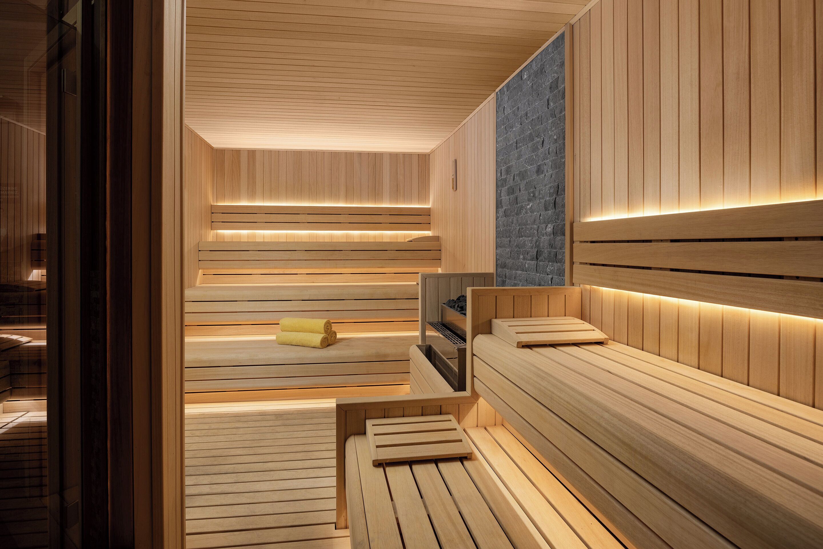 A sauna with wooden benches and a stone wall.
